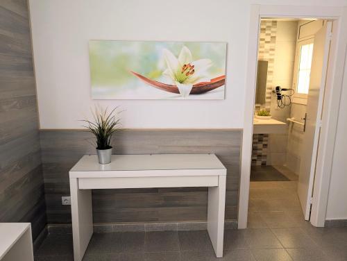 a white table with a flower painting on the wall at Apartamento Martin in Tossa de Mar