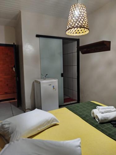 a room with a bed and a refrigerator and a light at Pouso Trindade in Trindade