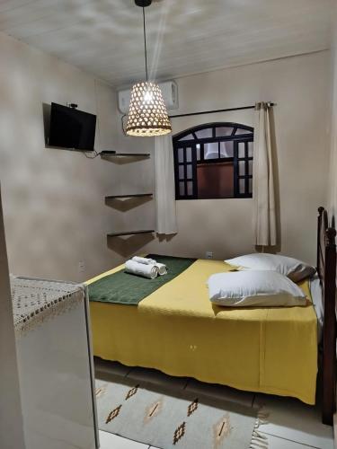 a bedroom with a large yellow bed with a tv on the wall at Pouso Trindade in Trindade