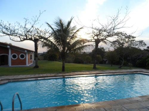 een zwembad met palmbomen en een huis bij Chacara Casa de Campo in Tietê