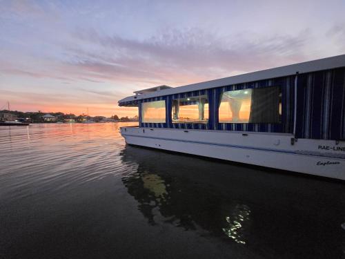 a boat is docked on the water at sunset at Liquid Spirit Noosaville houseboat " EXPERIENCE MORE " in Noosa Heads