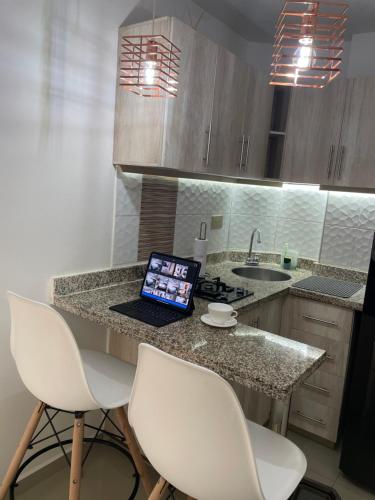 a kitchen with a laptop on a counter with chairs at Luxury liv Gran limonar in Cali