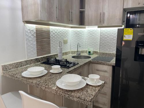 a kitchen with a counter with white dishes on it at Luxury liv Gran limonar in Cali