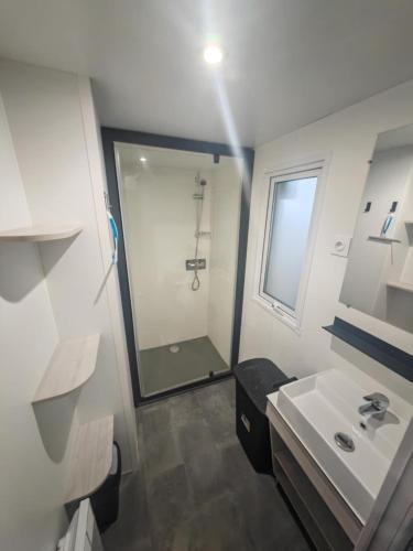 une salle de bain blanche avec une douche et un lavabo dans l'établissement Mobile home camping les sables d'or, au Grau-dʼAgde