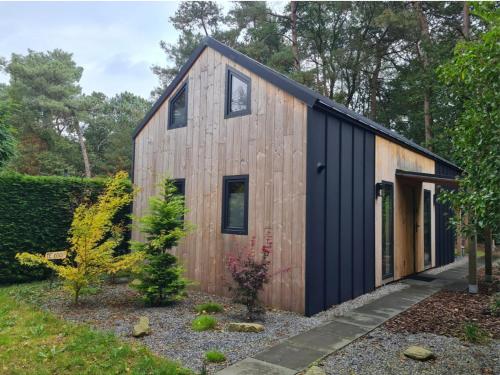 a wooden house with a black roof at Forest View Lodge Diessen in Diessen