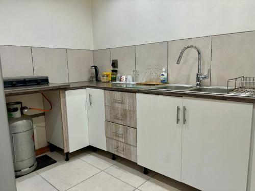 Una cocina con gabinetes blancos y un fregadero. en One Bedroom House, en Goodwood