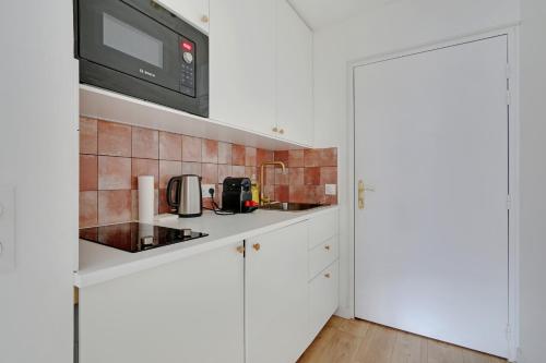 une cuisine avec des armoires blanches et un micro-ondes dans l'établissement Lovely Studio in Paris, à Paris