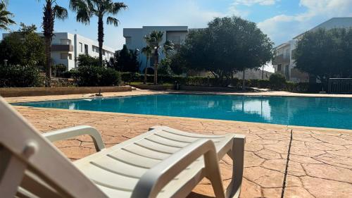 a white bench sitting next to a swimming pool at Luxe Appartement - vue sur montagne Plage, Piscine & Jeux pour Enfants in Imi Ouaddar