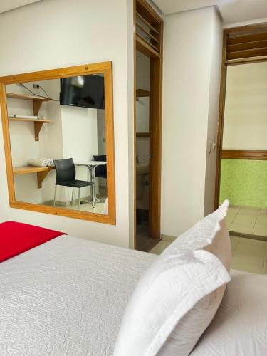 a bedroom with a bed and a mirror and a table at Hotel Portal Central in Medellín