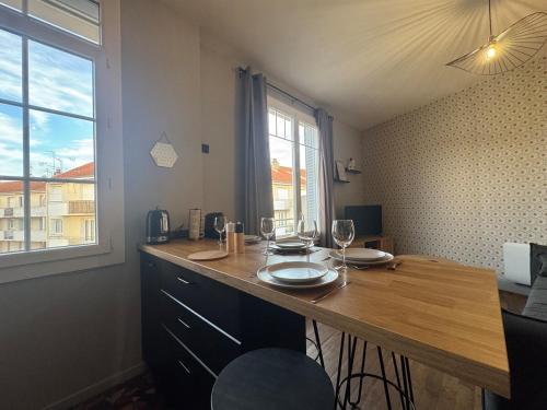 - une cuisine avec un comptoir en bois et une table avec des verres à vin dans l'établissement Le petit Lyautey - Retro-chic atmosphere, à Vichy