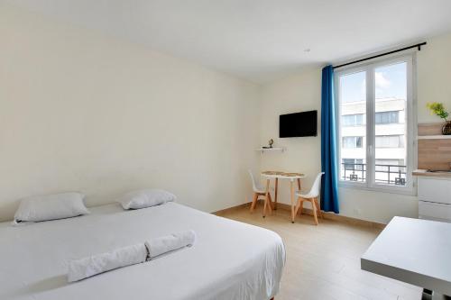 une chambre blanche avec un lit et une table dans l'établissement Charmant Studio Aubervilliers, à Aubervilliers