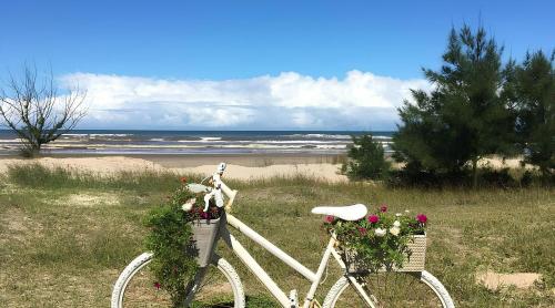 a white bike with flowers in baskets on a beach at Casa de praia na Paraíso in Torres