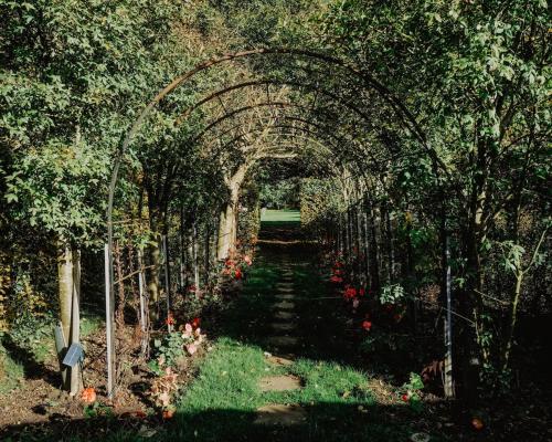 an archway in a garden with flowers and plants at Mind The Gap in Preston