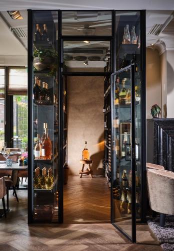 a room with glass shelves filled with wine bottles at Hotel de Leijhof Oisterwijk in Oisterwijk