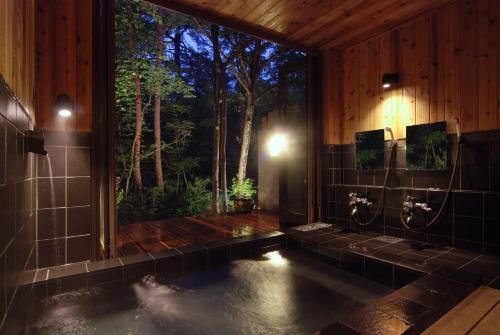 a bathroom with a large window and a pool of water at Pension Tomato in Hakuba