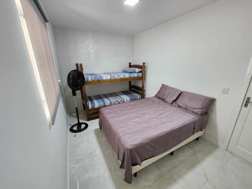 a small bedroom with a bed and a fan at Apartamento-3 pé na areia, churrasqueira, acesso a lagoa, vista para rio, Torres e serra gaúcha in Passo de Torres
