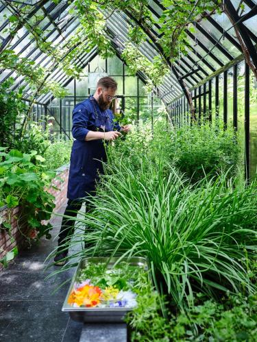 a man standing in a greenhouse looking at his cell phone at Hotel de Leijhof Oisterwijk in Oisterwijk