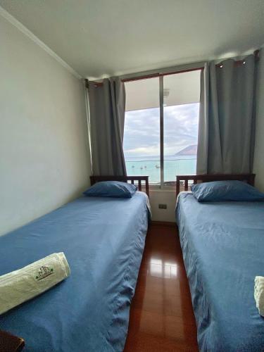 two beds in a room with a view of the ocean at Apartamento Alma Capital in Iquique