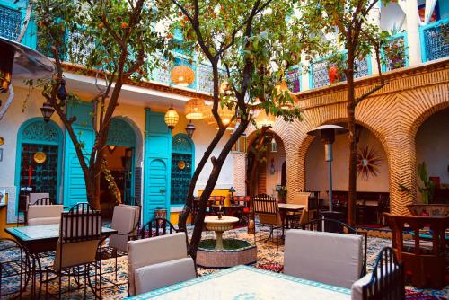 an outdoor patio with tables and chairs and trees at Riad Al Nour in Marrakech