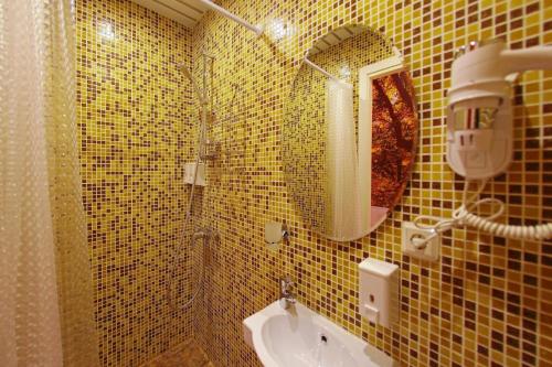 a yellow tiled bathroom with a sink and a mirror at Amore in Saint Petersburg