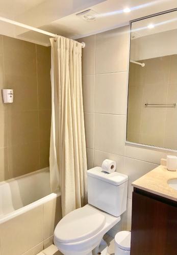 a bathroom with a toilet and a tub and a sink at Apartamento Alma Capital in Iquique
