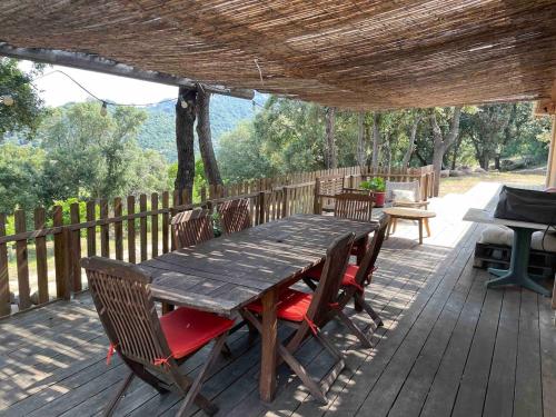 une table et des chaises en bois sur une terrasse en bois dans l'établissement Jolie maison familiale au cœur des vignes, à Sartène