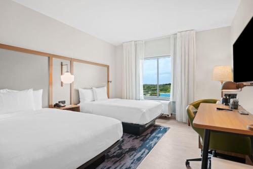 a hotel room with two beds and a desk at Fairfield Inn & Suites Fort Lauderdale Airport & Cruise Port in Dania Beach