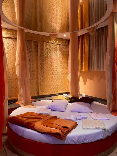 a bed with a blanket on it in front of a window at Heru's Motel in Poços de Caldas