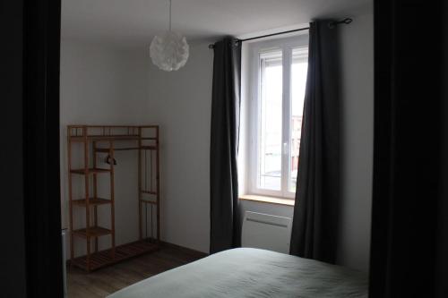 une chambre avec un lit et une fenêtre avec des rideaux dans l'établissement Appartement Béthune Proche Gare, à Béthune