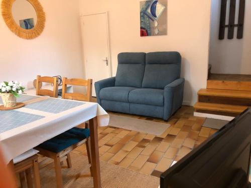 a living room with a blue couch and a table at Petite maison avec terrasse in Jurançon
