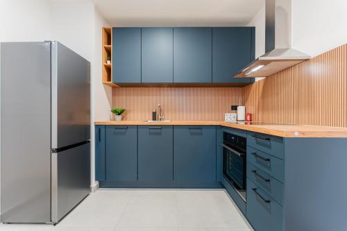 Una cocina con gabinetes azules y un refrigerador. en Flex SelfCheckIns 138 - Zagreb - Bedroom - Parking - Loggia, en Zagreb
