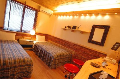 a room with two beds and a table and a mirror at Pension Tomato in Hakuba