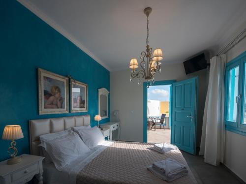 フィラにあるヴィラ ローズの青い壁のベッドルーム1室、ベッド1台、シャンデリアが備わります。