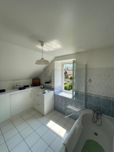 La salle de bains blanche est pourvue d'une baignoire et d'une fenêtre. dans l'établissement Le temps des gabariers, à Monceaux-sur-Dordogne