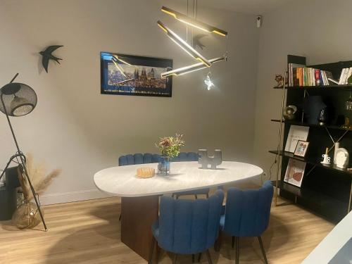 une salle à manger avec une table blanche et des chaises bleues dans l'établissement Maison Jardin des Plantes Le Mans, au Mans
