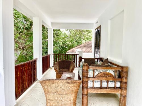 a porch with wicker chairs and a table on a balcony at VITA'S BEACH House in Diani Beach