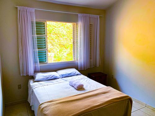 a small bedroom with a bed with a window at Pousada Pontal de Escarpas in Capitólio