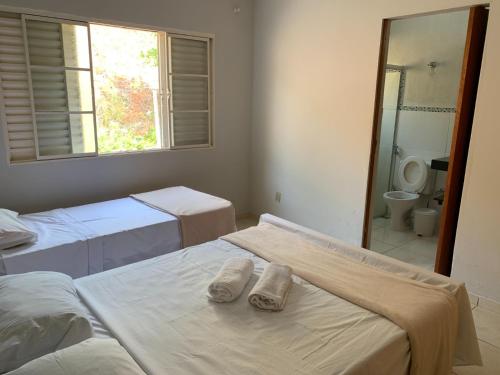 a room with two beds and a bathroom with a mirror at Pousada Pontal de Escarpas in Capitólio