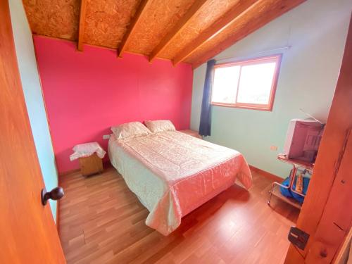 a bedroom with a bed and a red wall at Habitaciones S&E in Coihaique