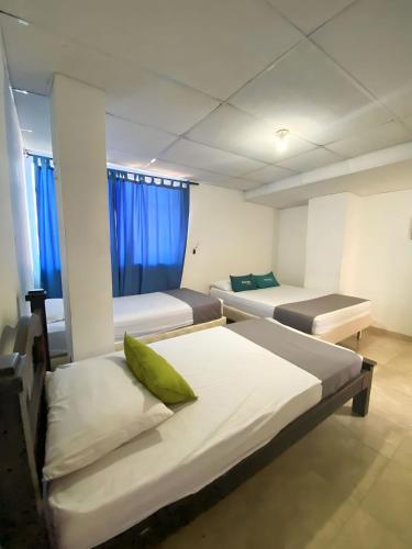 two beds in a room with blue curtains at Hotel Puerto Vigia Inn in Cartagena de Indias
