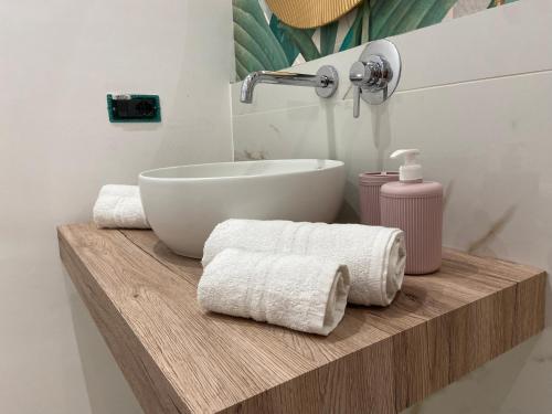 un bagno con lavandino e asciugamani su una mensola in legno di Villa Gioia a Realmonte