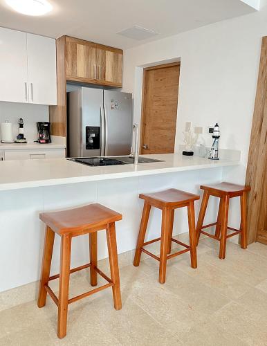 a kitchen with two wooden stools and a counter top at Xeliter Green One Playa Dorada in San Felipe de Puerto Plata