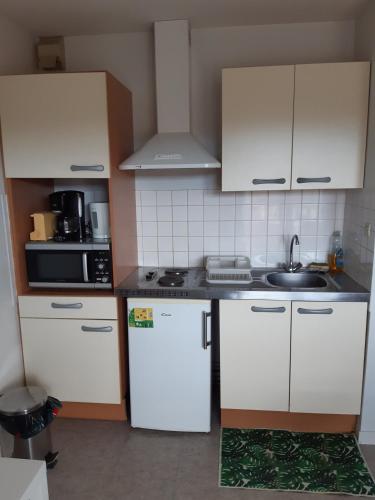 une cuisine avec des armoires blanches et un évier dans l'établissement Les Alisiers 26, à Eugénie-les-Bains