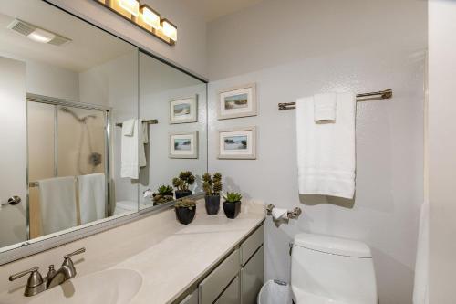 a white bathroom with a sink and a mirror at Oceanfront Sea'batical - SBTC212 in Solana Beach