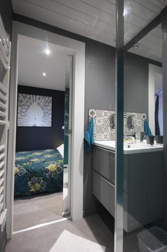 a bathroom with a sink and a bedroom with a bed at L'Appart - Résidence Chez Gally à Angers in Les Ponts-de-Cé