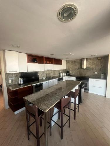 Capelas Beach House في Las Garzas: مطبخ به طاولة كبيرة وبعض الكراسي