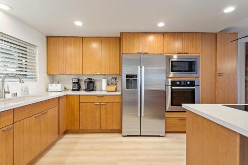 a kitchen with wooden cabinets and stainless steel appliances at Don't Worry Beach Happy SONG13 in Solana Beach