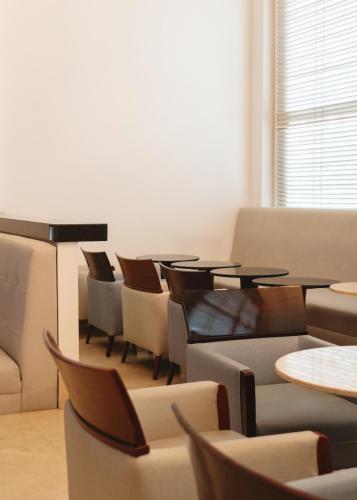 a waiting room with tables and chairs and a window at Hotel Dann Carlton Barranquilla y Centro de Convenciones in Barranquilla