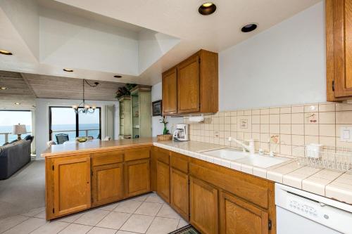 a kitchen with wooden cabinets and a view of the ocean at Escape at Seascape - SUR112 in Solana Beach