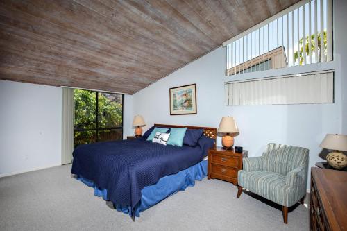 a bedroom with a bed and a chair and a window at Escape at Seascape - SUR112 in Solana Beach